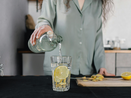 Glass of water with lemon, promoting hydration for mental and physical health.